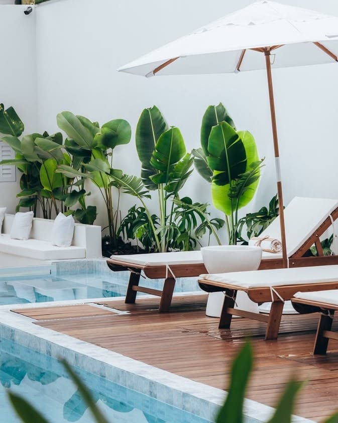 A piscina e o deck de madeira do OLISA Boutique Hotel, com espreguiçadeiras e plantas tropicais