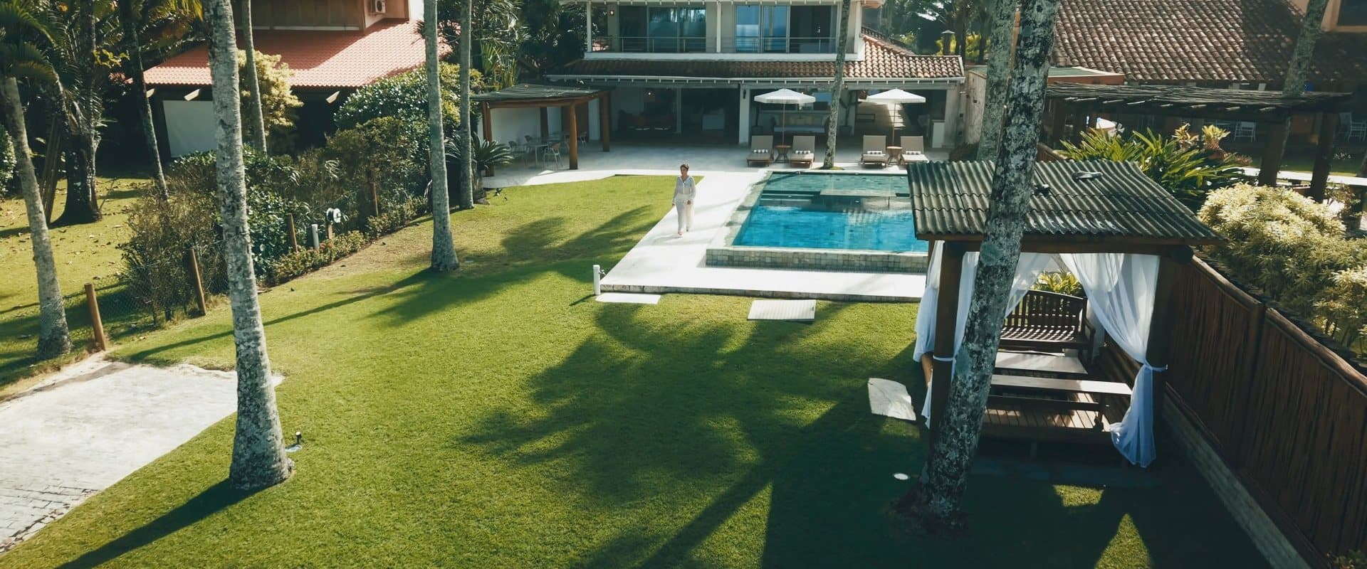 O jardim do OLISA Al Mar entre as palmeiras, com a piscina e o hotel ao fundo