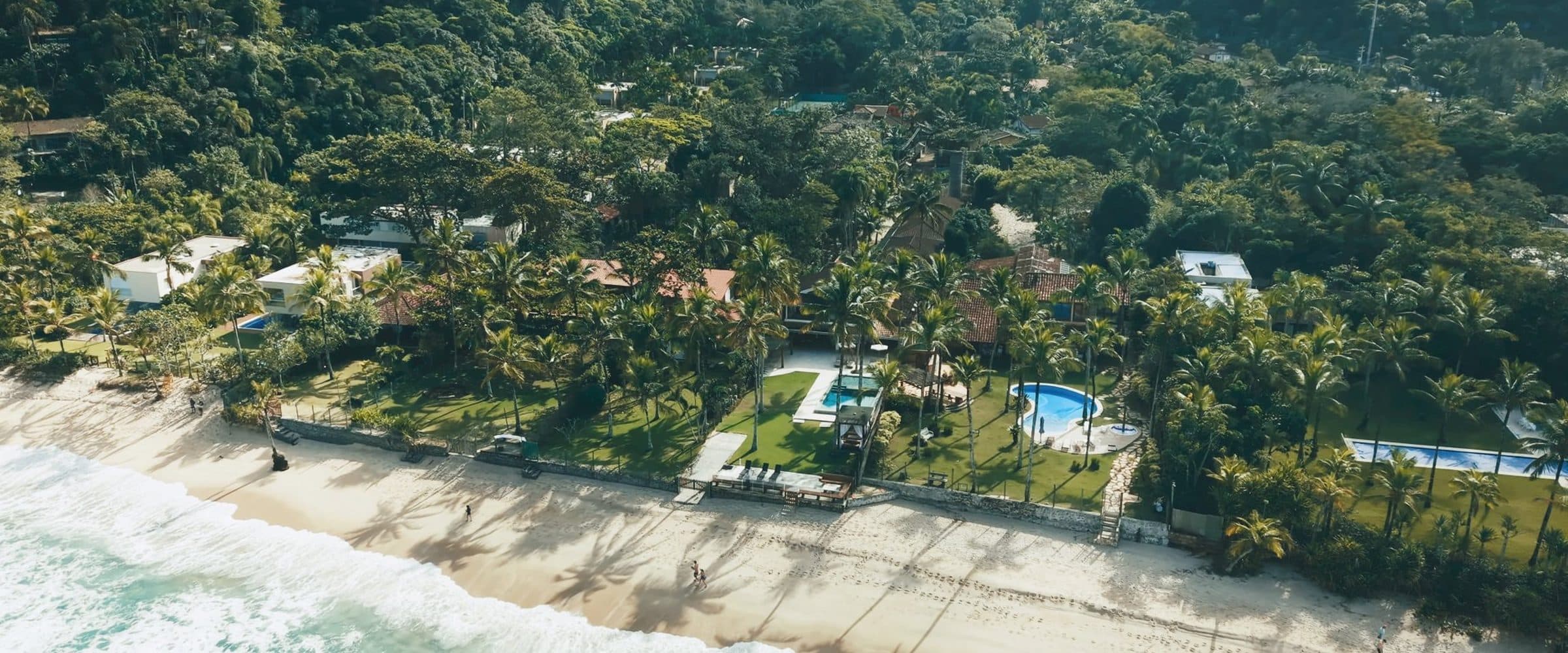 Vista aérea da praia de Maresias, com a faixa de hotéis entre a mata e o mar