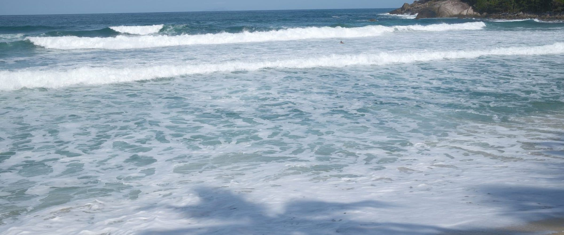 A praia de Maresias, com a arrebentação e a ponta de pedras ao fundo